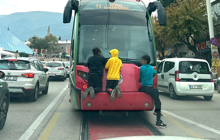 Bursa’da ölümle burun buruna yolculuk! Bursa'da dört çocuk, seyir halindeki tramvayın arkasına tutunarak tehlikeli bir